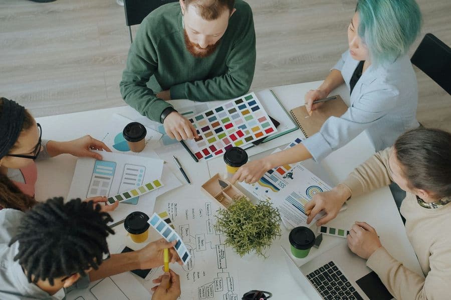 Overhead view of a creative marketing team working with colour swatches, layouts and charts
