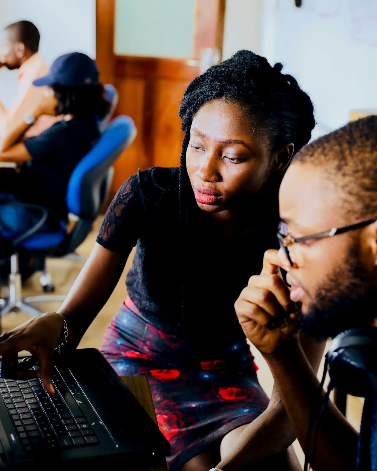 Two participants pair-work at one laptop, discussing what is on screen
